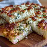 Hearty Fluffy Cottage Cheese Flatbread stacked on a wooden board, warm and tender, ideal for dipping in hummus.