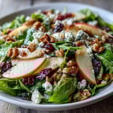 A close-up of the Mixed Greens and Apple Bowl showing vibrant red apple slices and crumbled feta over crisp greens.