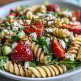 Bright and refreshing Spring Pasta Salad with Strawberries, Feta, and Arugula, tossed in balsamic dressing and topped with basil.  
