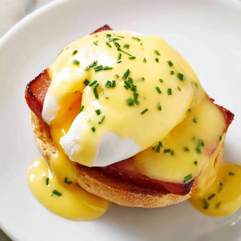 Golden Eggs Benedict with runny yolks and velvety hollandaise sauce.