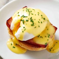 Golden Eggs Benedict with runny yolks and velvety hollandaise sauce.